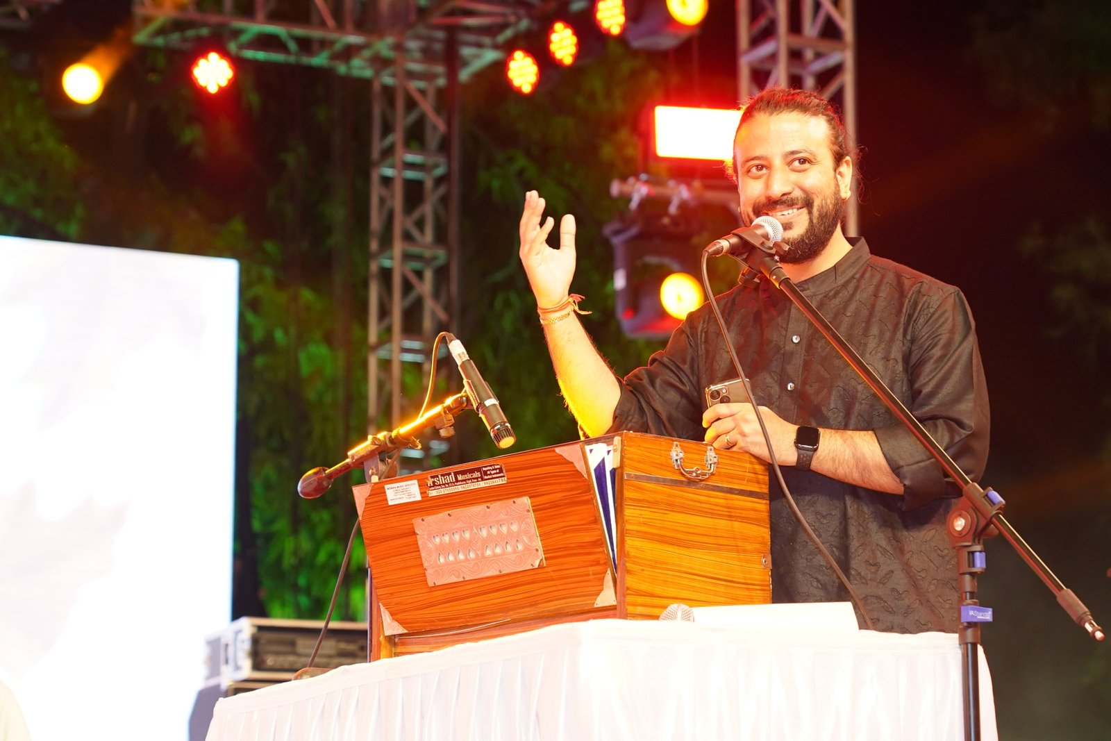 Saurabh Zadoo performing on an open-air stage, one hand raised to the audience