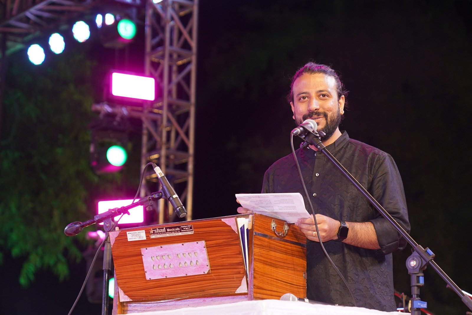 Saurabh Zadoo at the harmonium reading a score under coloured stage lights